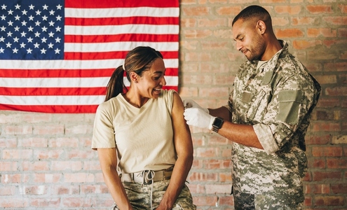 Medic applying a band aid to a soldiers arm after vaccination