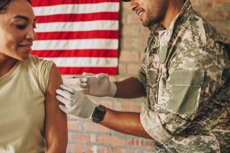 Army medic injecting a female soldier with the covid 19 vaccine