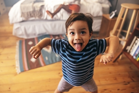 Cute young boy flexing his strength at home