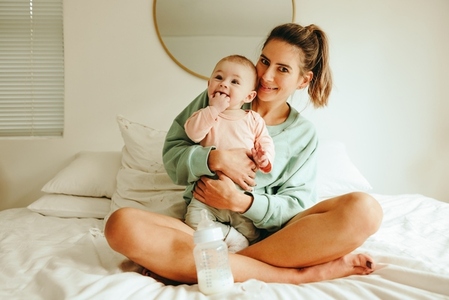 Happy mother holding her baby on the bed