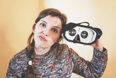 Funny portrait of a young woman holding a cardboard vr glasses