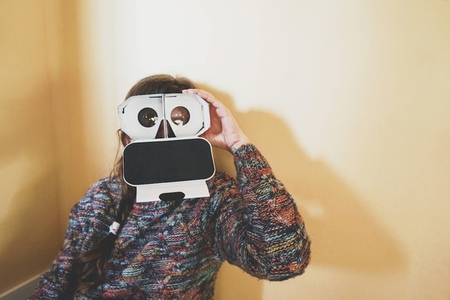 Image of a young woman showing the inside of a cardboard vr glas
