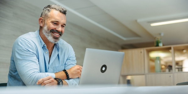 Cheerful businessman attending an online meeting in an office