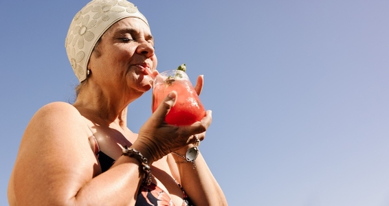 Senior woman enjoying a tiki cocktail on a sunny day