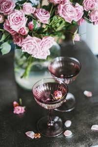 Champagne in glasses and tender pink roses bouquet in vase