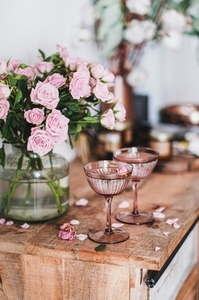 Champagne in glasses and tender pink roses bouquet in vase