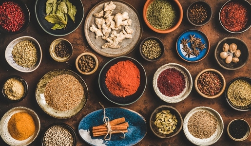 Flat lay of different spices in bowls over rusty background