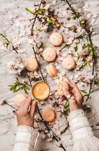 Womans hands holding macaron cookies and fresh coffee