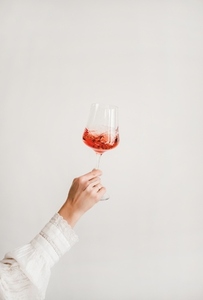 Womans hand holding and turning glass of rose wine