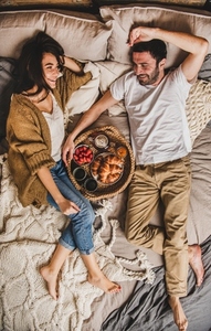 Young happy couple lying on blankets and having breakfast