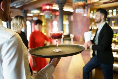 Waiter serving a cocktail for elegant clients in a nice bar