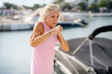 Older woman doing shadow boxing outdoors  Senior female doing sport in a coastal port