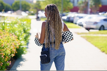 Black woman with colourful braided hairstyle  wearing a skateboard