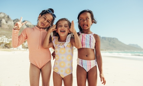 Playful little girls making funny faces at the beach