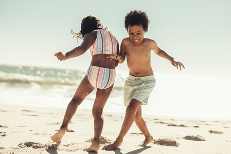 Active little kids playing together on beach sand