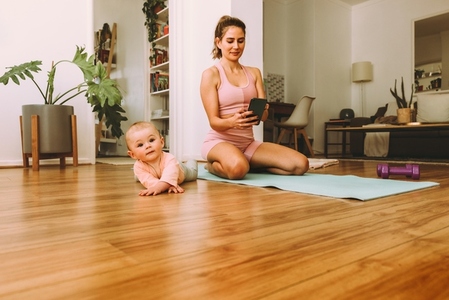 Healthy mom using fitness app while working out with her baby
