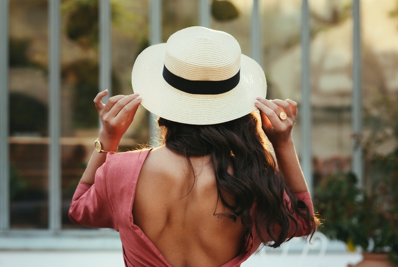 Rearview of a young woman posing in a summer hat