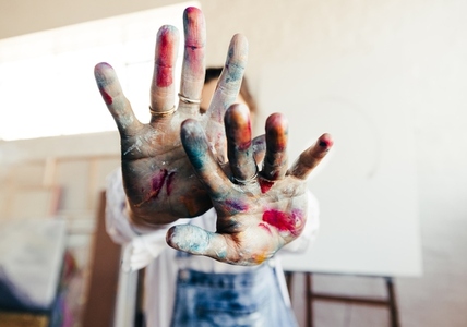 Painter blocking the camera with her colour painted hands