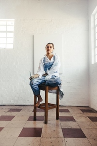 Young painter sitting on a chair in her art studio