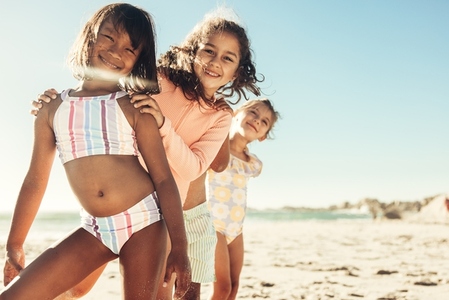 Three active little girls having fun together at the beach