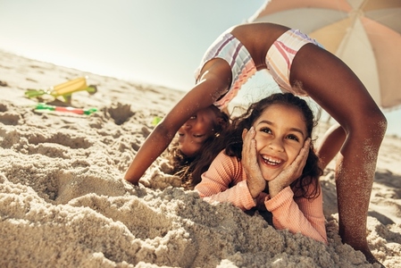 Creative little girls having fun together at the beach