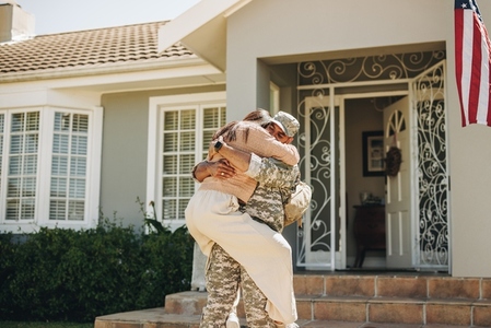 Happy soldier reuniting with his wife at home