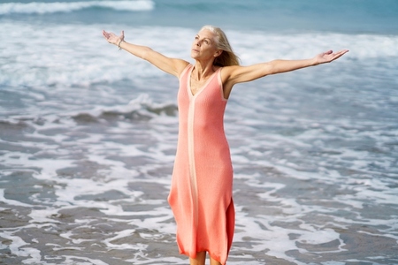 Beautiful mature woman opening her arms on a beautiful beach  enjoying her free time