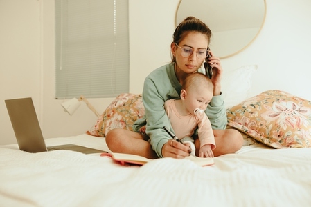 New mom taking a phone call while sitting with her baby