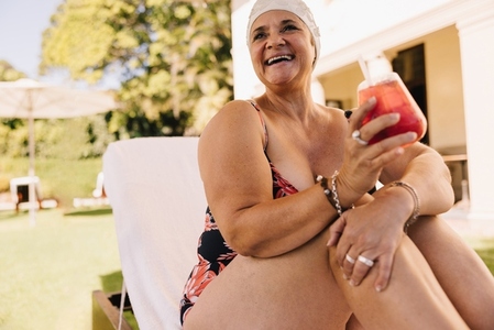 Happy senior woman relaxing on a lounger at a tropical spa resort