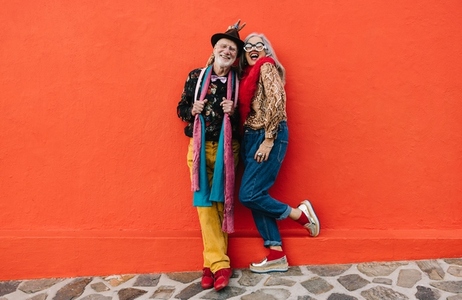 Senior couple laughing cheerfully against a red wall