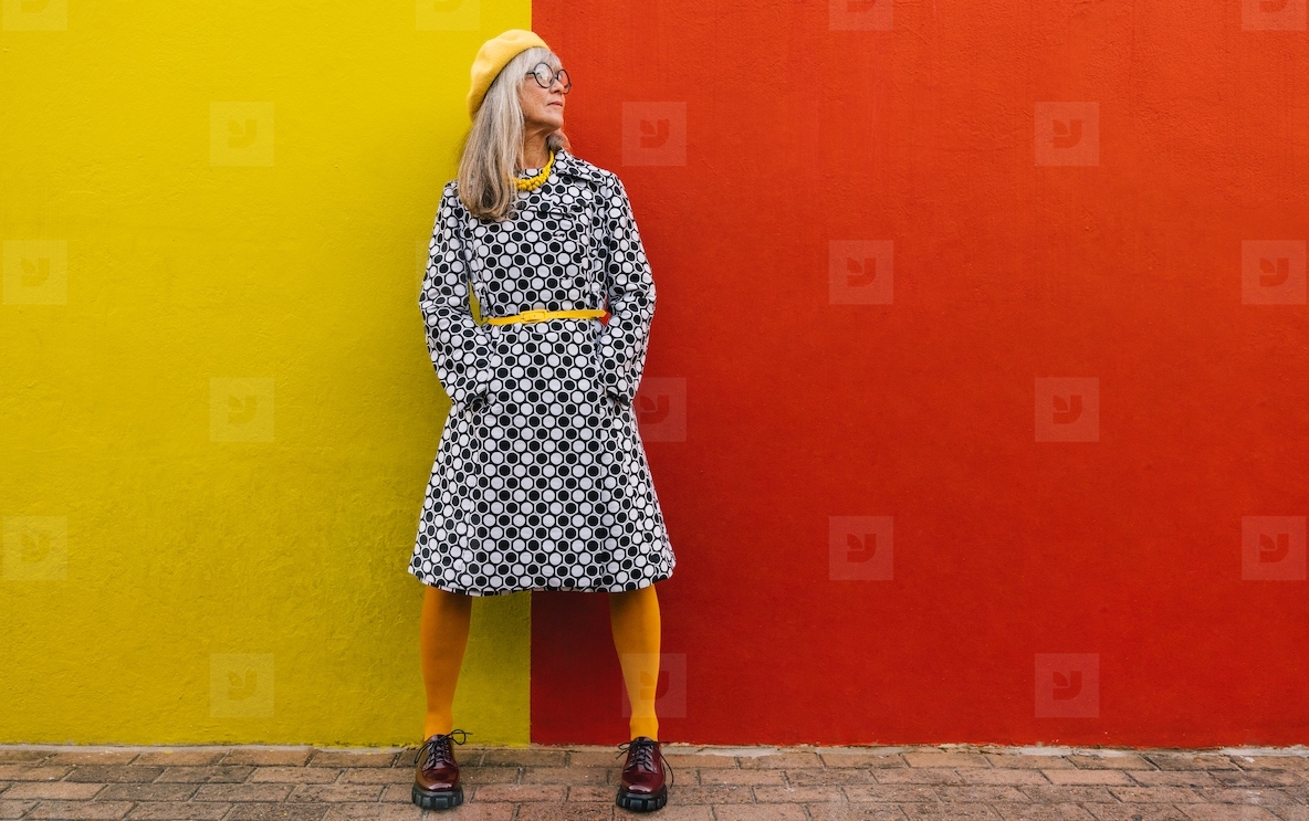 Mature woman looking away thoughtfully against a colourful wall