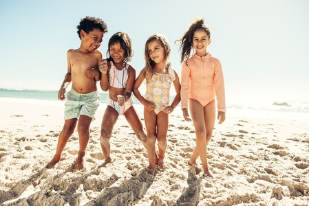 Active little kids playing together on beach sand