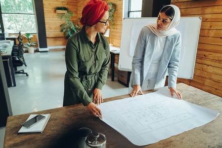Muslim designers working with a blueprint drawing in an office