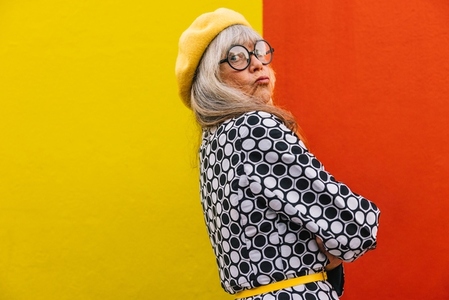 Funny elderly woman pouting her lips against a colourful background