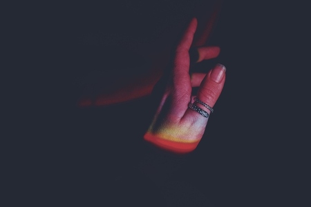 Detail of human hands illuminated by colorful lights