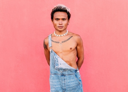 Portrait of a young handsome guy with bare chest looking at camera at pink wall