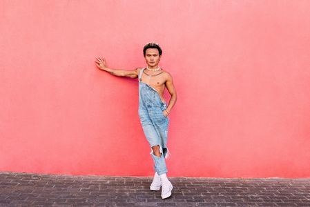 Stylish guy leaning a pink wall looking at camera  Young handsome man standing outdoors