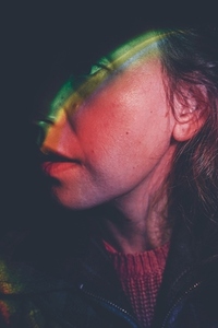 Artistic portrait of a young woman illuminated by colored lights