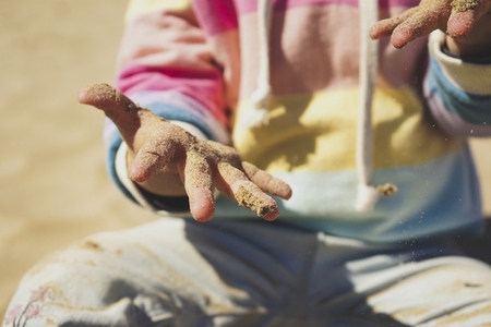 Close up of a little girl playing with the sand at the beach