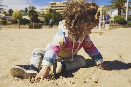 Young toddler playing with the sand at the beach
