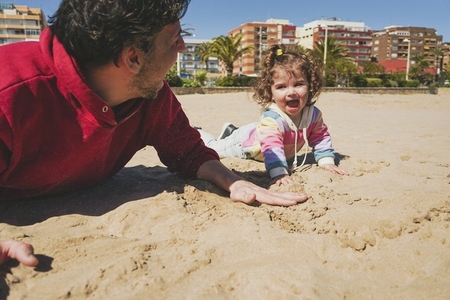 Little girl playing on the sand with her dad