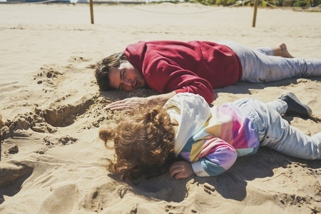 Little girl playing on the sand with her dad
