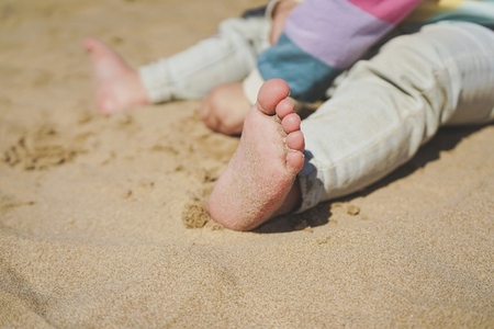 Close up of the feet of a toddler with sand of the beach