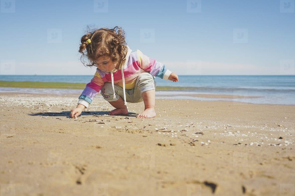 Wide view of a little girl wearing rainbow hoodie playing at the