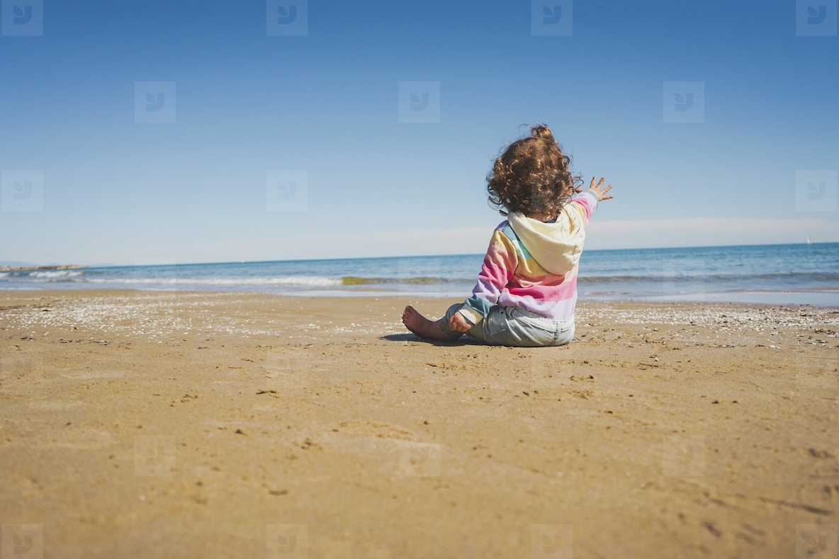 Wide view of a little girl wearing rainbow hoodie playing at the