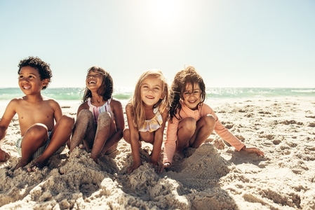 Happy young children playing with beach sand