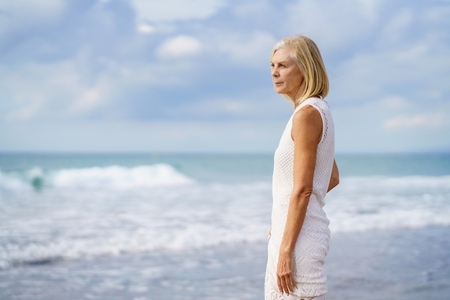 Mature woman gazing serenely at the sea  Elderly female standing at a seaside location