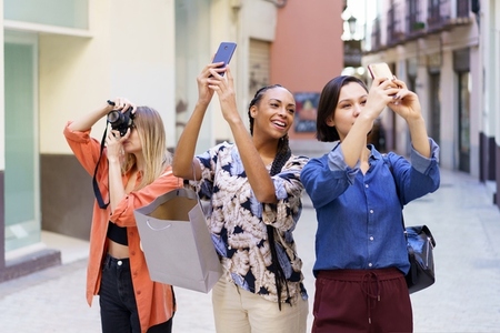 Content multiracial friends taking photos of street