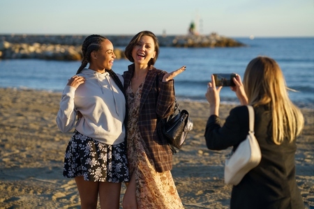 Woman taking photo of laughing diverse girlfriends