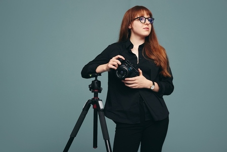 Photographer standing next to her tripod in a studio
